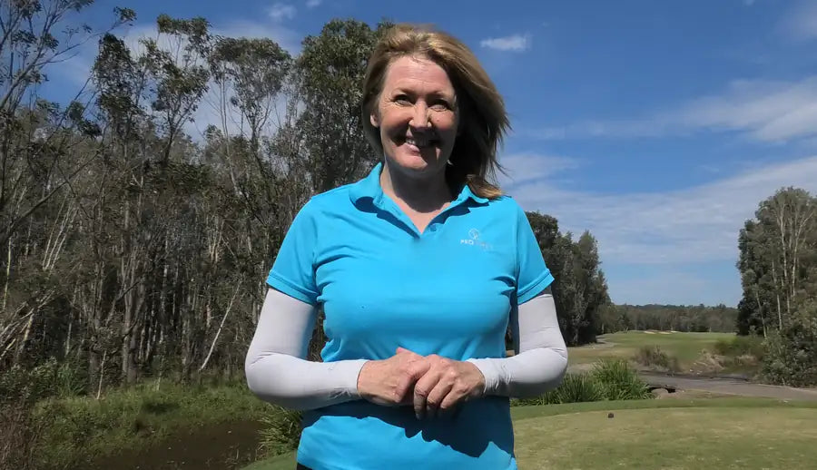 Anne Rollo wearing white arm sleeves beside a golf green.
