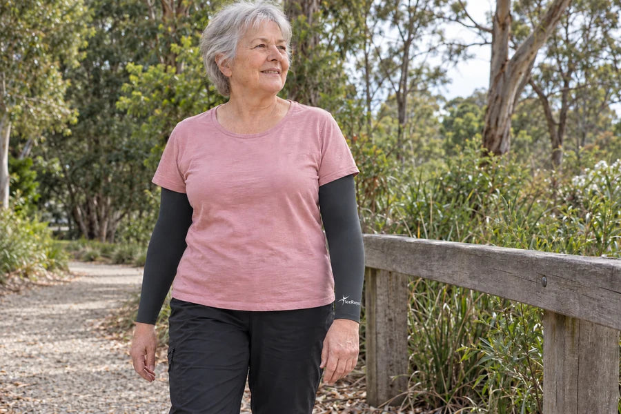 Woman wearing charcoal IceRays arm sleeves beside a timber rail on a walking track.