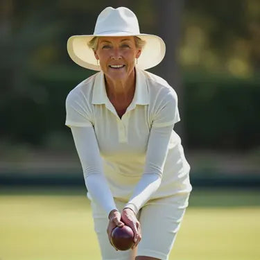 Bowler wearing white arm sleeves while holding a bowl on the green.
